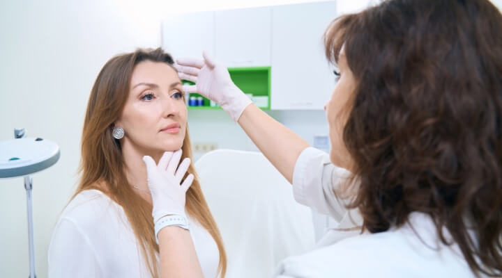 white female doctor examining white female patient's face