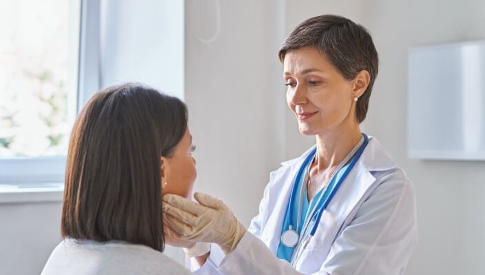 female doctor examining female patient's face